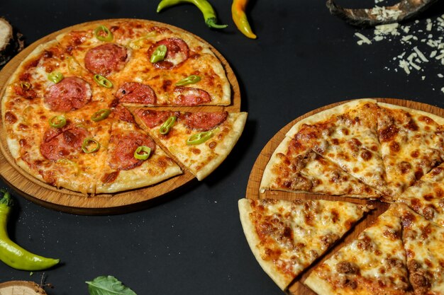 Vue latérale de la pizza à la viande avec pizza au salami sur des supports avec du piment
