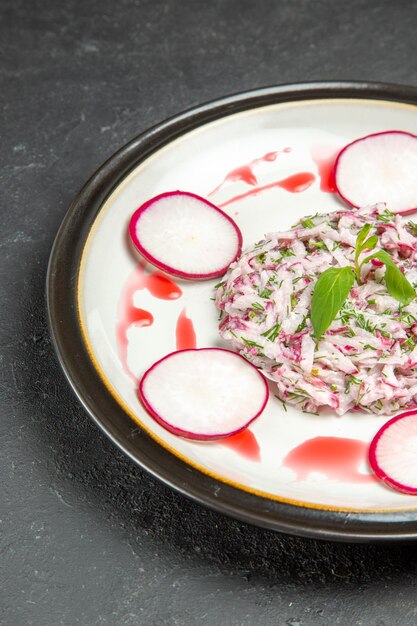 Vue latérale d'un plat appétissant de radis et d'herbes avec sauce sur la plaque