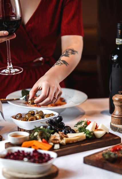 Photo gratuite vue latérale d'un plateau de fromages avec raisins et olives marinées