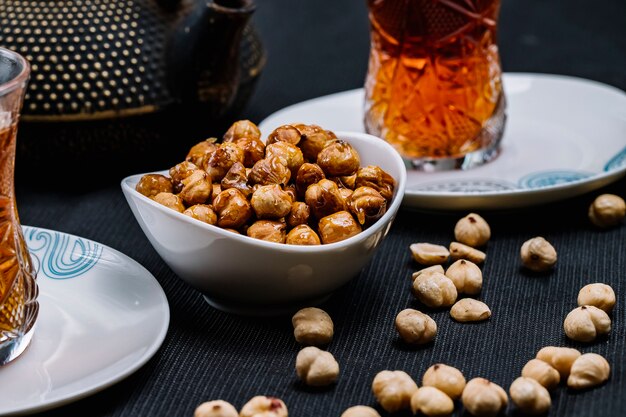 Vue latérale pois chiches rôtis leblebi avec sel et thé noir sur la table