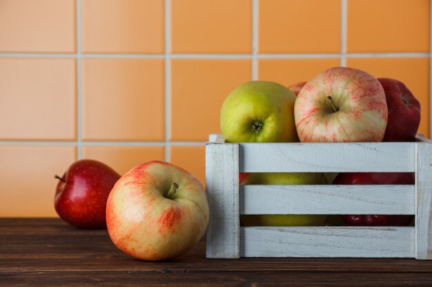 Vue latérale des pommes dans une boîte en bois sur fond de carreaux orange. espace horizontal pour le texte