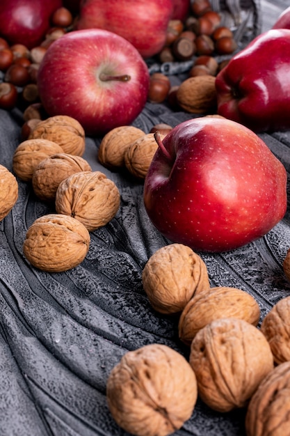 Photo gratuite vue latérale pommes rouges aux noix et noix sur gris