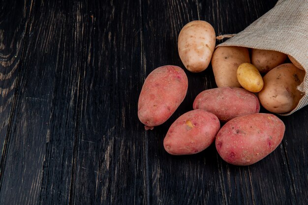 Vue latérale des pommes de terre débordant de sac sur table en bois avec espace copie