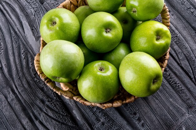 Vue latérale des pommes vertes dans un panier de paille beige