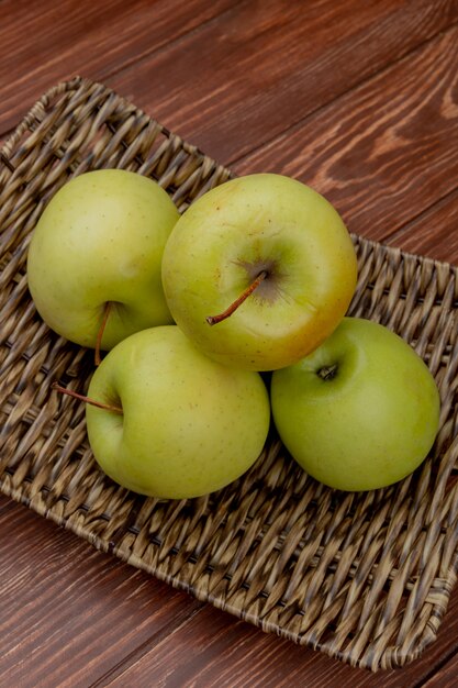 Vue latérale des pommes vertes dans la plaque de panier sur la surface en bois