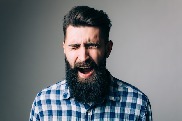 Photo gratuite vue latérale portrait d'homme barbu hurlant - mur gris