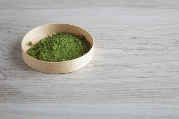 Vue latérale de la poudre de thé matcha premium bio dans une boîte en bois isolé sur blanc tableau simple seul