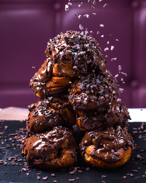 Vue latérale de profiterole avec des flocons de chocolat et du sirop