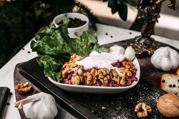 Vue latérale de la salade de betteraves aux noix et à la crème sure sur une planche de bois