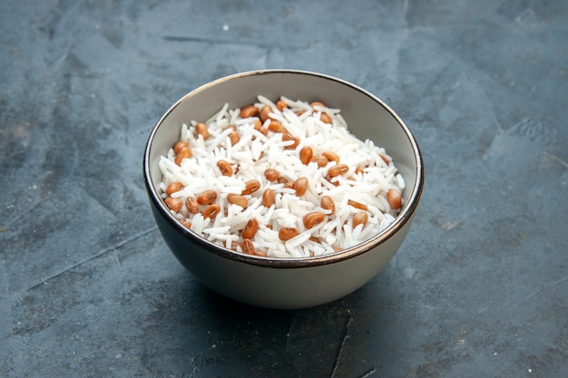 Vue latérale d'un savoureux repas de riz avec des haricots dans un petit pot marron sur fond bleu