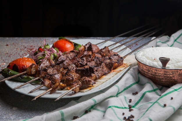 Photo gratuite vue latérale shish kebab sur des brochettes avec tomate et oignon et ayran en plaque blanche