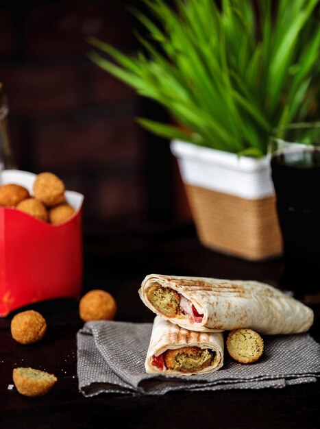 Vue latérale si le pain au poulet roule avec des légumes sur une planche de bois