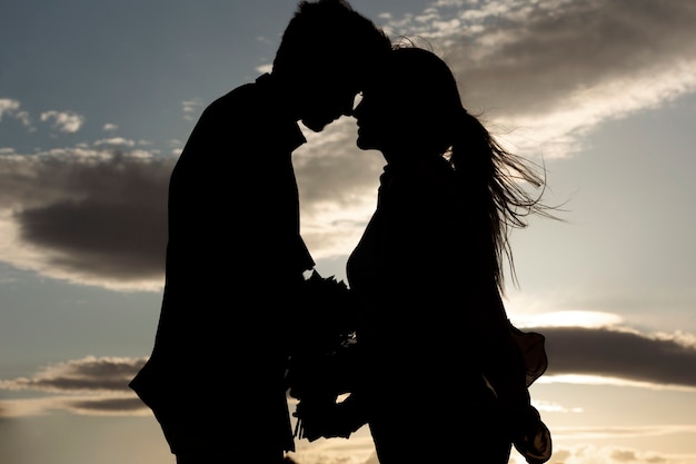 Photo gratuite vue latérale des silhouettes de couple romantique avec des fleurs