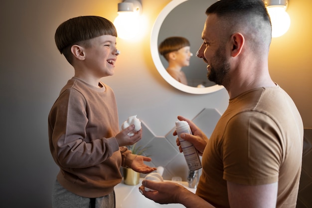 Vue latérale smiley enfant et père dans la salle de bain