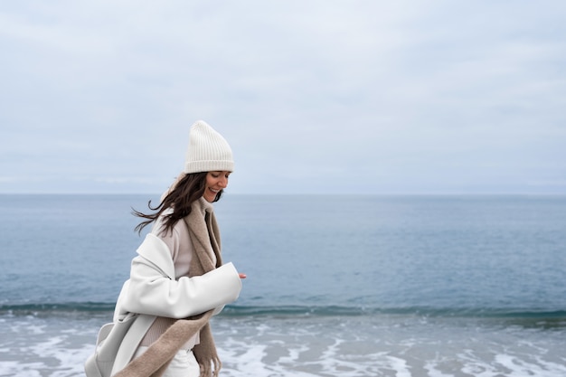 Vue latérale smiley femme marchant sur la plage