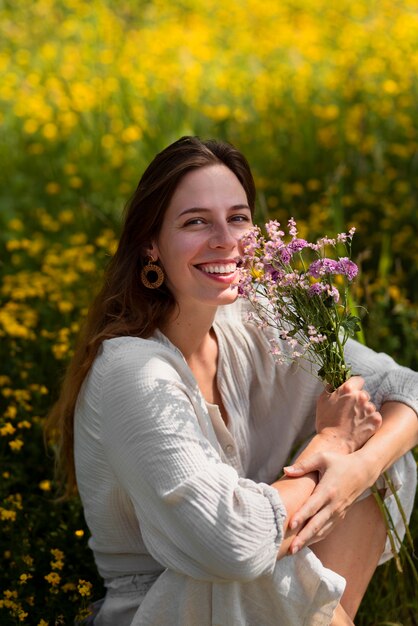 Vue latérale smiley femme tenant des fleurs violettes