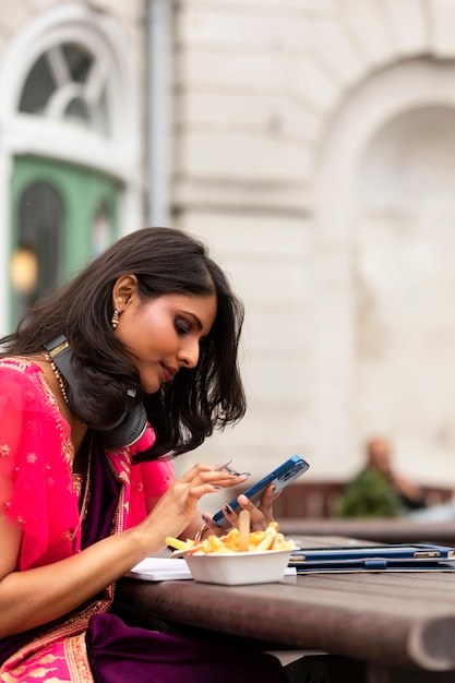 Vue latérale smiley femme tenant un smartphone