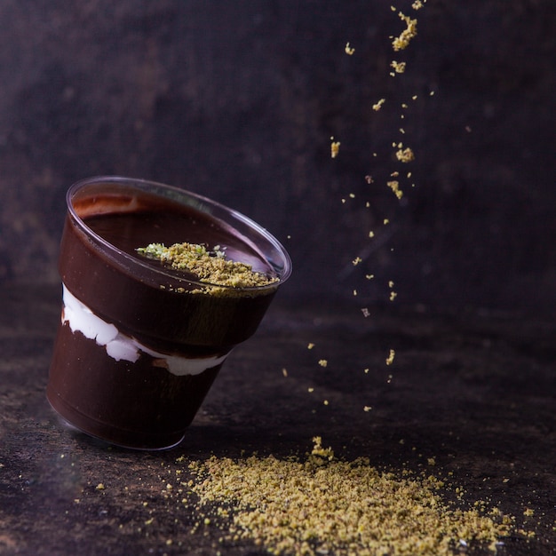 Vue latérale smoothie au chocolat avec des miettes de noix dans une tasse en plastique