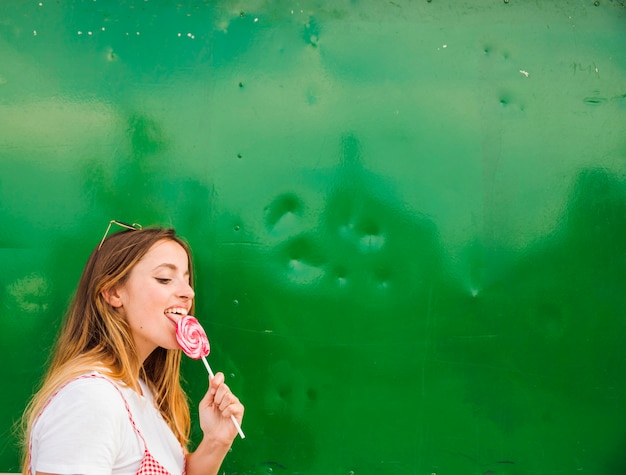 Vue Latérale D'une Sucette Lécher Une Jeune Femme Sur Fond Vert