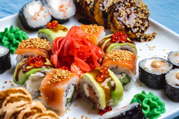 Vue latérale sushi set philadelphia avec saumon dragon roll avec avocat gingembre et wasabi sur une plaque