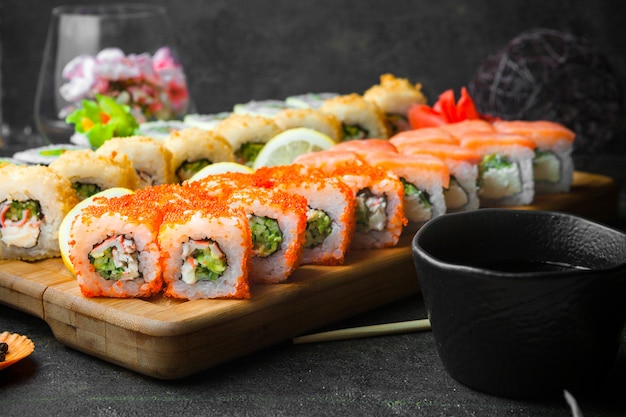 Vue latérale des sushis avec sauce soja et baguettes dans une planche de service en bois