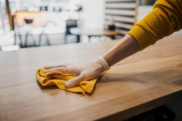 Vue latérale de la table de nettoyage barista tout en portant des gants en latex