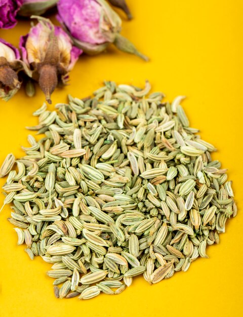 Vue latérale d'un tas de graines d'anis séchées avec des boutons de rose de thé sur fond jaune