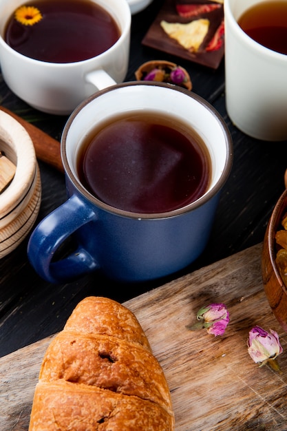 Vue latérale d'une tasse de thé avec croissant sur rustique