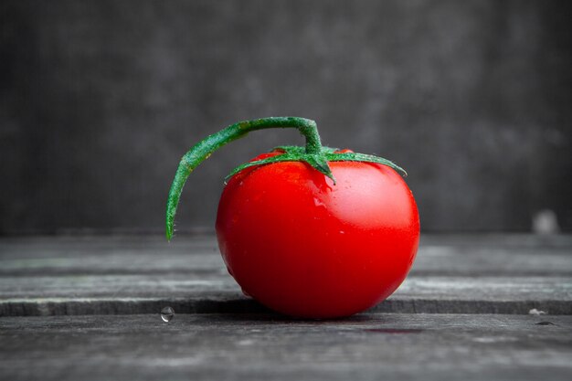 Vue latérale tomate sur fond sombre en bois et texturé. horizontal