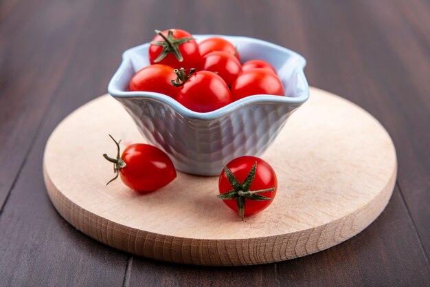 Vue latérale des tomates dans un bol sur une planche à découper et bois