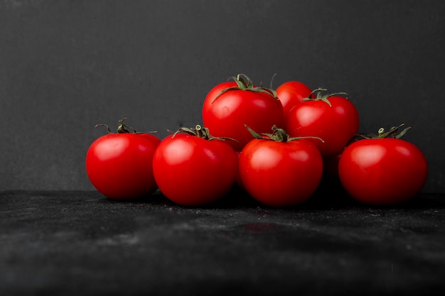 Vue latérale de tomates fraîches sur fond noir