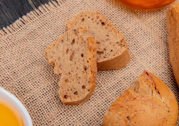 Vue latérale des tranches de baguette noire avec du beurre fondu sur un sac