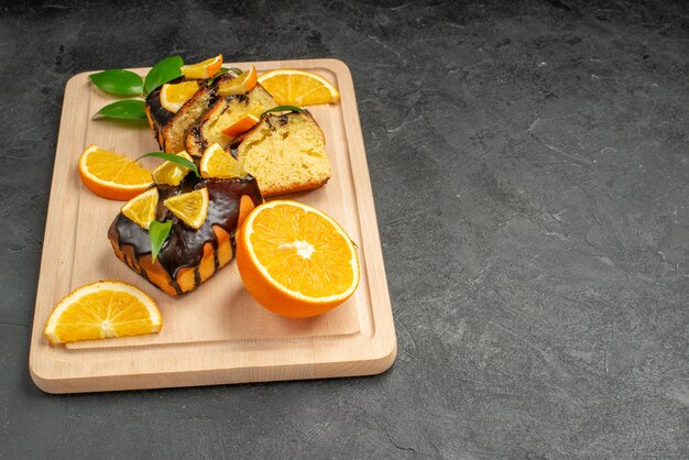 Vue latérale des tranches de citron frais et des tranches de gâteau hachées fraîchement cuites sur table sombre