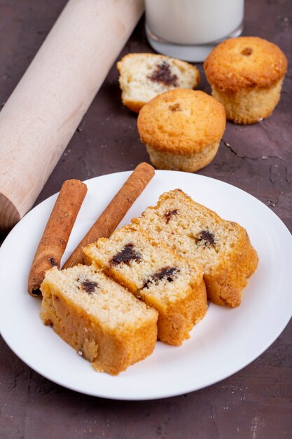 Vue latérale des tranches de gâteau éponge avec des bâtons de cannelle sur une plaque blanche