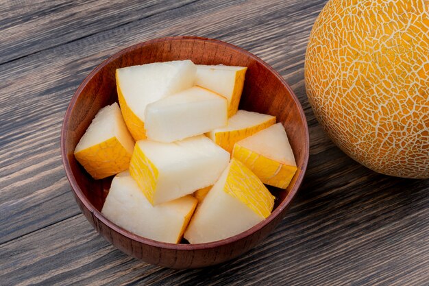 Vue latérale des tranches de melon dans un bol avec un tout sur fond de bois avec copie espace