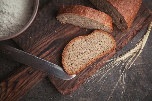 Vue latérale des tranches de pain avec un couteau sur une planche à découper et brun foncé.