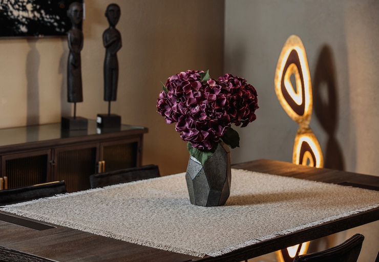 Photo gratuit vue latérale d'un vase noir moderne avec des fleurs violettes sur une nappe sur la table