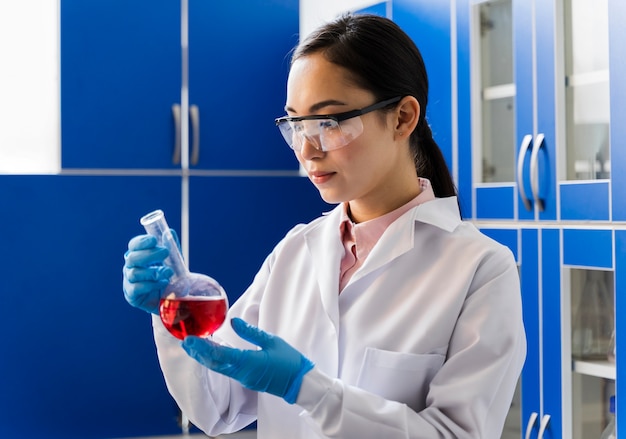 Photo gratuite vue latérale de la verrerie de laboratoire scientifique féminin avec substance