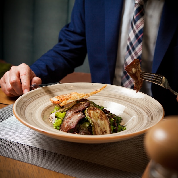 Photo gratuite vue latérale de la viande frite avec des courgettes frites et des craquelins et la main humaine et une fourchette dans une assiette ronde