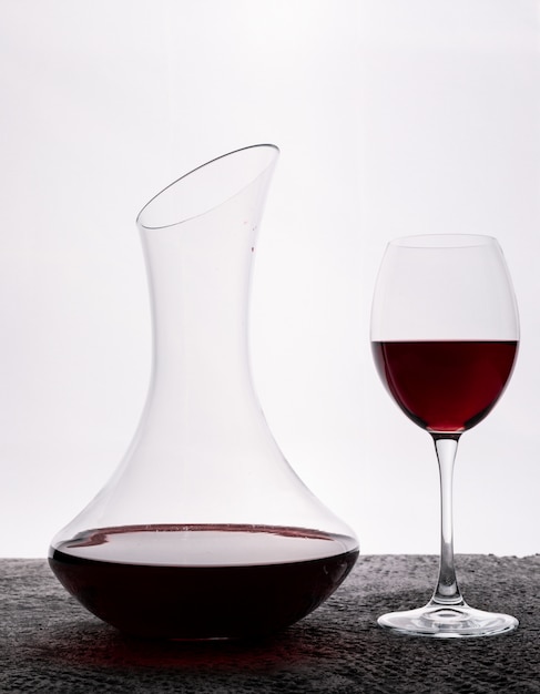 Vue latérale vin rouge avec verre sur blanc vertical