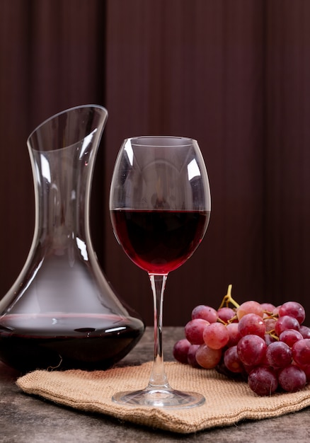 Vue latérale vin rouge en verre avec raisin vertical