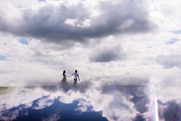 Vue de loin les jeunes mariés marchent dans les nuages