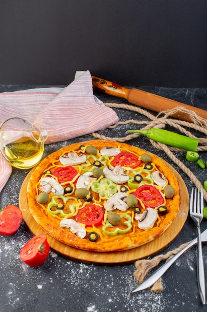 Vue lointaine avant savoureuse pizza aux tomates rouges, olives vertes et champignons avec des tomates fraîches partout dans le bureau gris
