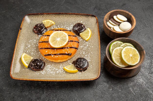 Vue à mi-hauteur délicieuse tarte sucrée avec sauce au chocolat et tranches de citron sur fond gris tarte à gâteau pâte à biscuits biscuit sucré