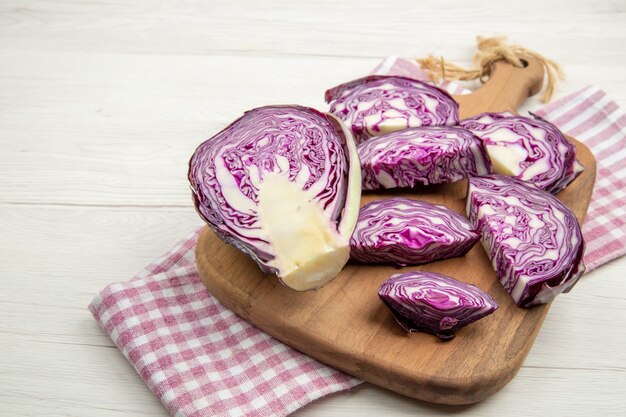 Photo gratuite vue de la moitié inférieure du chou rouge haché sur une planche à découper sur un torchon à carreaux rose et blanc sur une table grise