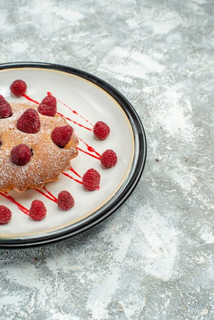 Vue de la moitié inférieure du gâteau aux baies sur une assiette ovale blanche sur une surface grise