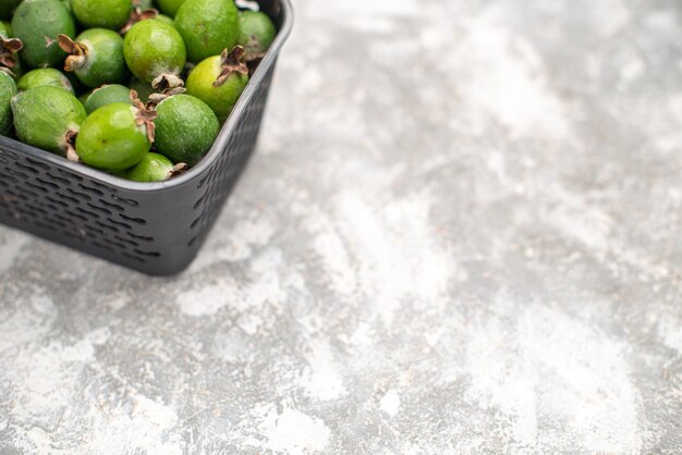 Vue de la moitié inférieure des feykhoas frais dans un panier sur une surface grise avec espace de copie