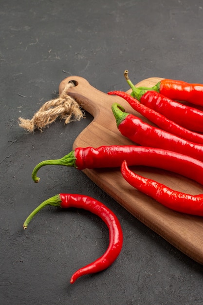 Vue de la moitié inférieure des piments rouges sur une planche à découper sur fond noir