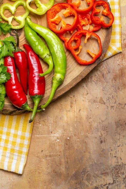 Vue de la moitié supérieure de différents légumes coupés en morceaux sur une planche de bois d'arbre ronde sur fond ambre