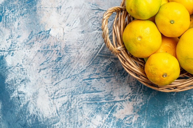 Photo gratuite vue de la moitié supérieure des mandarines fraîches sur panier en osier sur l'espace libre de surface blanc bleu